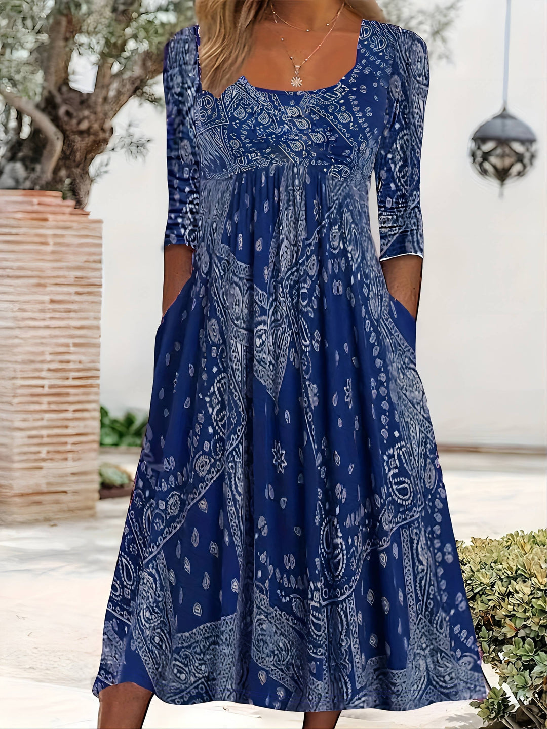 A woman wearing the Maureen long sleeve grey paisley midi dress with a square neckline and flowing skirt, styled for a relaxed day out.