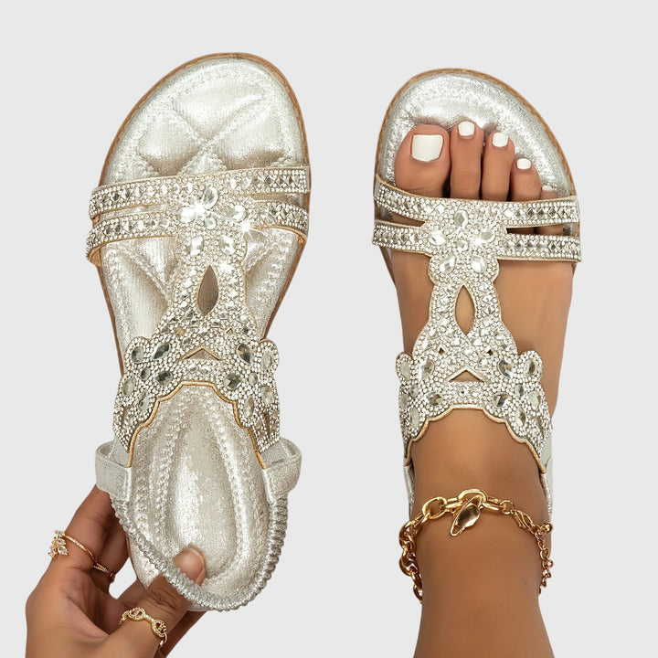 A woman wearing elegant gold open-front sandals with supportive straps and a cushioned sole.
