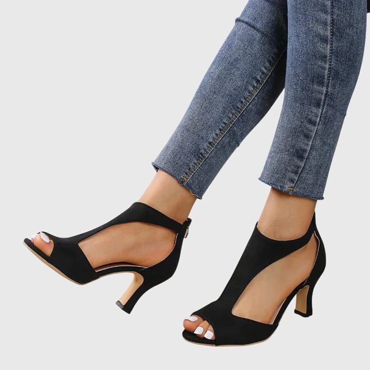 A woman wearing flexible orthopaedic heels, standing comfortably in a polished everyday outfit.