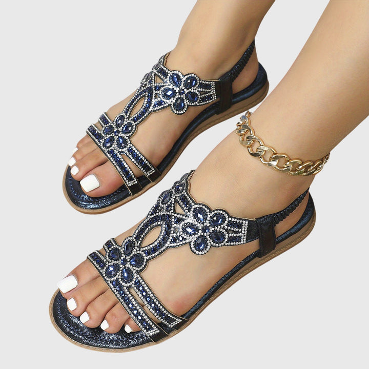 A woman wearing elegant gold open-front sandals with supportive straps and a cushioned sole.