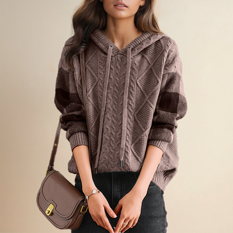 A woman wearing a soft cable-textured hooded jumper, cosy and warm with the hood down.