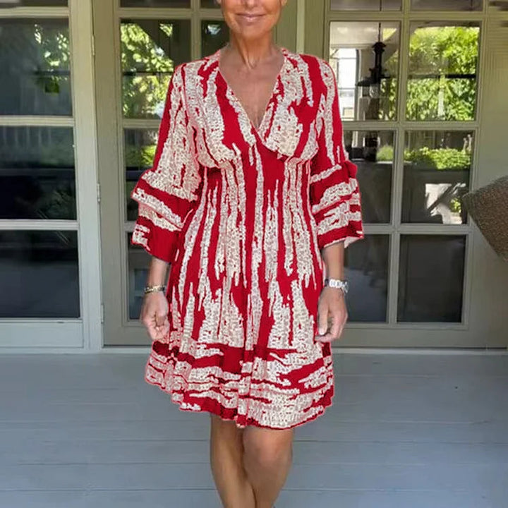 Woman wearing a boho print mini dress with ruffled sleeves and a soft V-neckline.