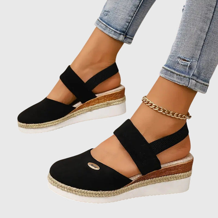 A woman walking comfortably in black cushioned support sandals with adjustable straps.