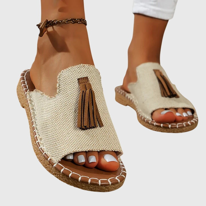 A woman wearing colourful patterned boho slides with tassel details on a holiday day out.