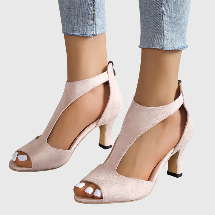 A woman wearing flexible orthopaedic heels, standing comfortably in a polished everyday outfit.