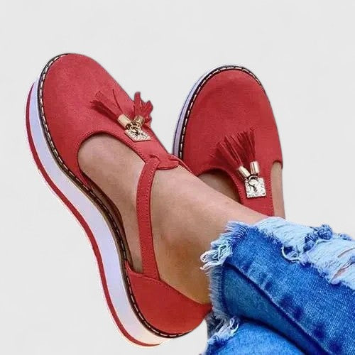 A woman wearing elegant supportive loafers with golden detail and tailored trousers, looking polished and at ease.