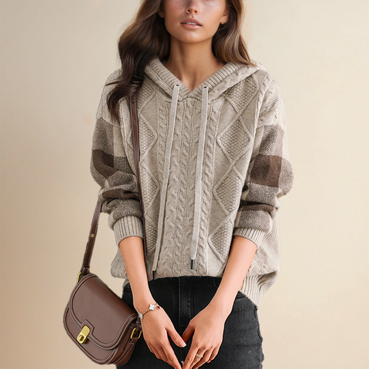 A woman wearing a soft cable-textured hooded jumper, cosy and warm with the hood down.