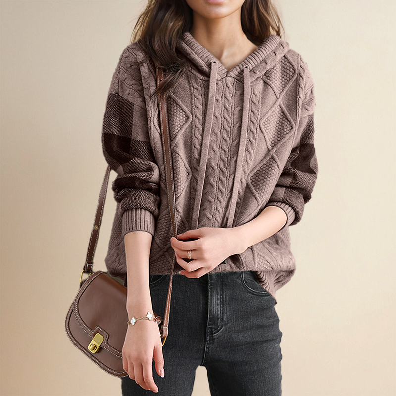 A woman wearing a soft cable-textured hooded jumper, cosy and warm with the hood down.