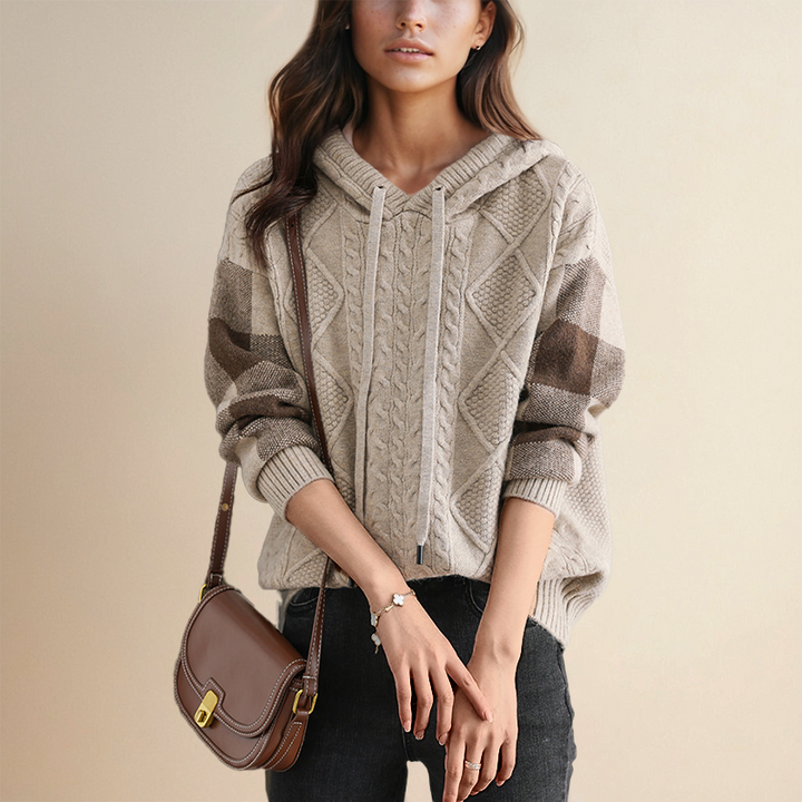 A woman wearing a soft cable-textured hooded jumper, cosy and warm with the hood down.
