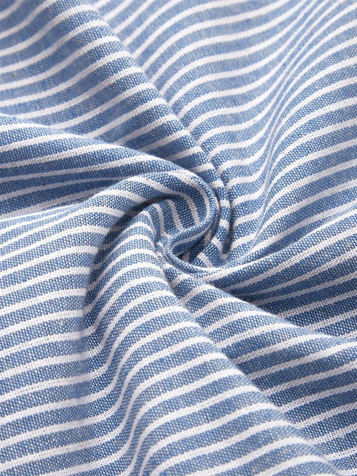 A woman wearing the Margaret striped midi dress with button details, standing outdoors on a bright day.