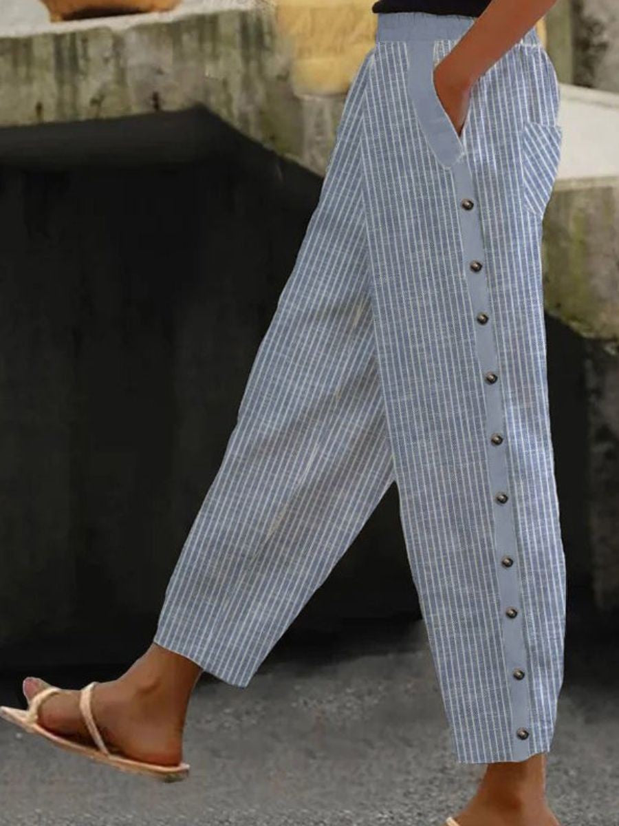 A woman wearing striped pull-on trousers with a side button detail and elastic waist.