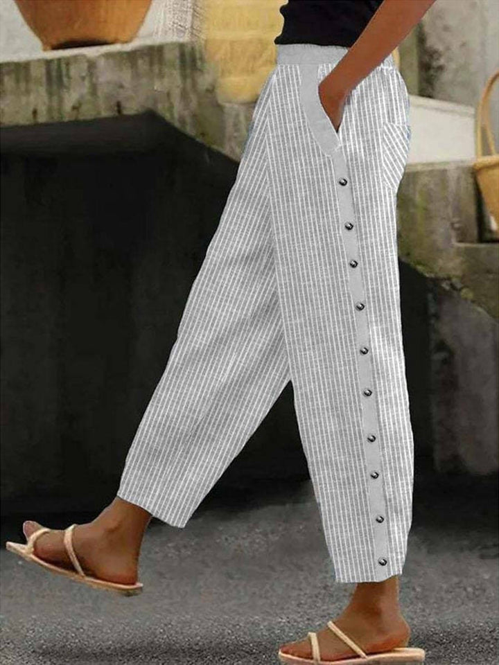 A woman wearing striped pull-on trousers with a side button detail and elastic waist.