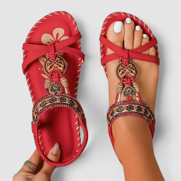 A woman wearing black beaded boho sandals with braided straps, a golden medallion and a stretchy slingback.