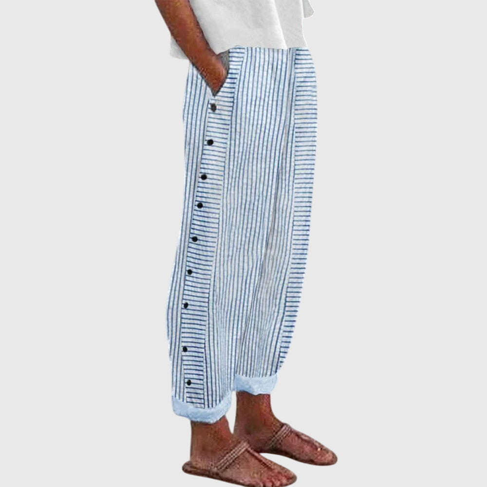 A woman wearing elegant everyday trousers in a fine blue stripe with a wide cut and side buttons.