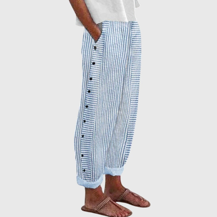 A woman wearing elegant everyday trousers in a fine blue stripe with a wide cut and side buttons.