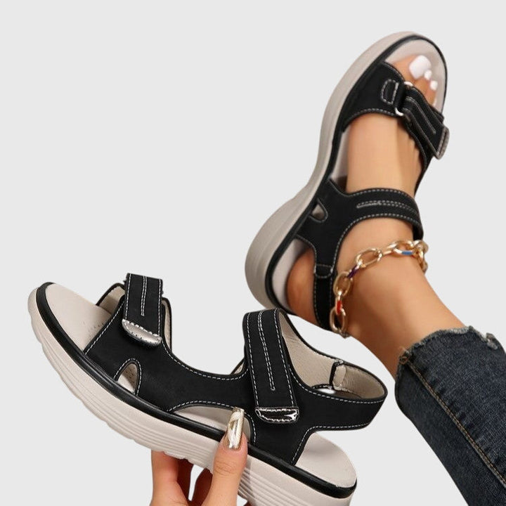 A woman in beige adjustable strap sandals standing steady and relaxed on a sunny path.