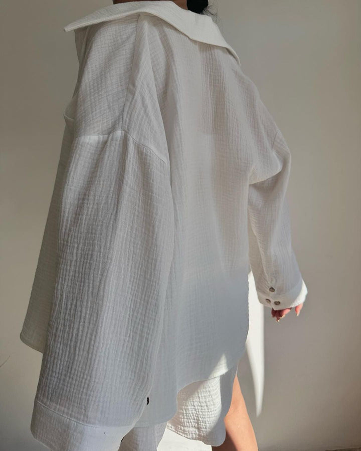 A woman wearing a flowing oversized shirt with drawstring shorts, relaxed and breezy.