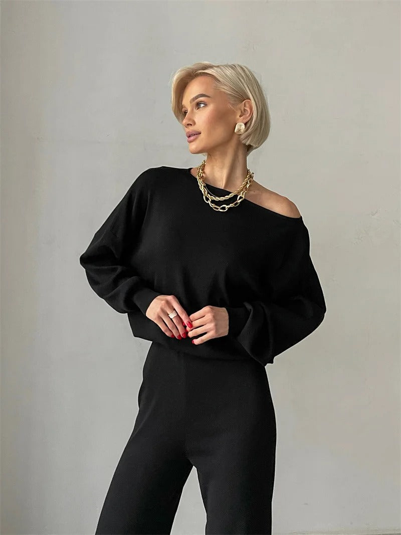 A woman wearing an off-shoulder draped top with wide-leg trousers