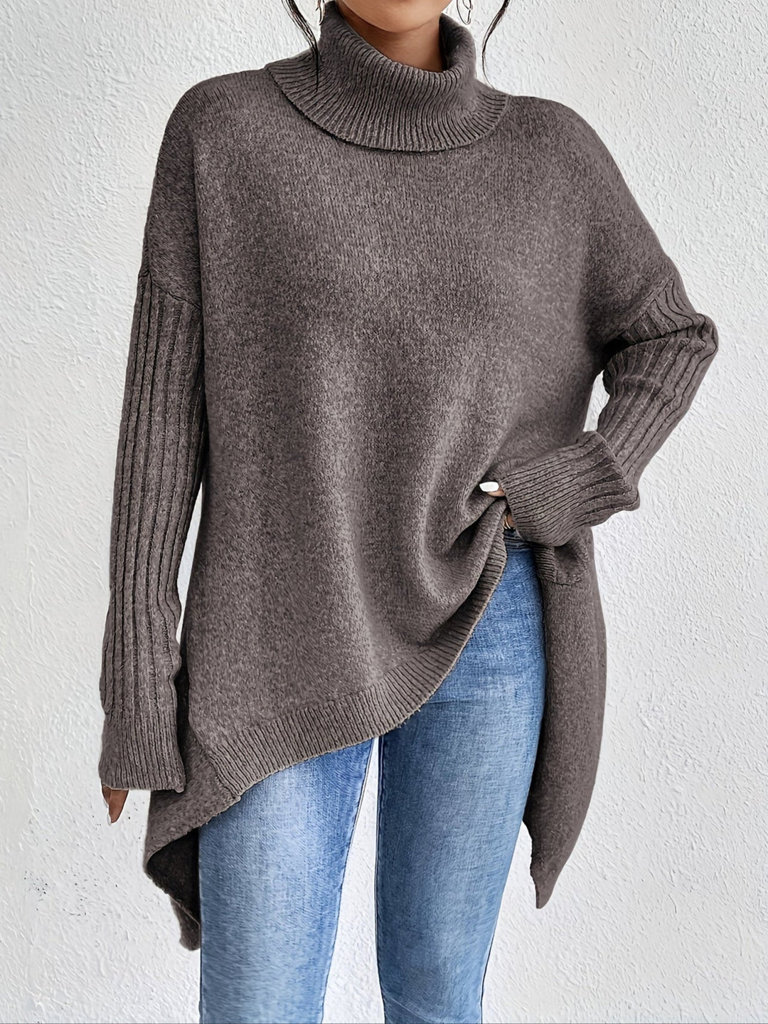 A woman wearing a stand-collar jumper with a chic asymmetric drape, warm and polished.