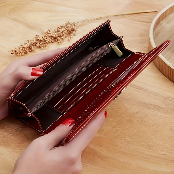A woman holding an open bifold wallet, tucking a card into its slot.