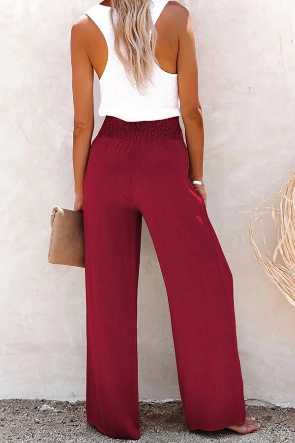 A woman in high-waisted loose wide-leg trousers with subtle button detailing, styled for an elegant everyday look.