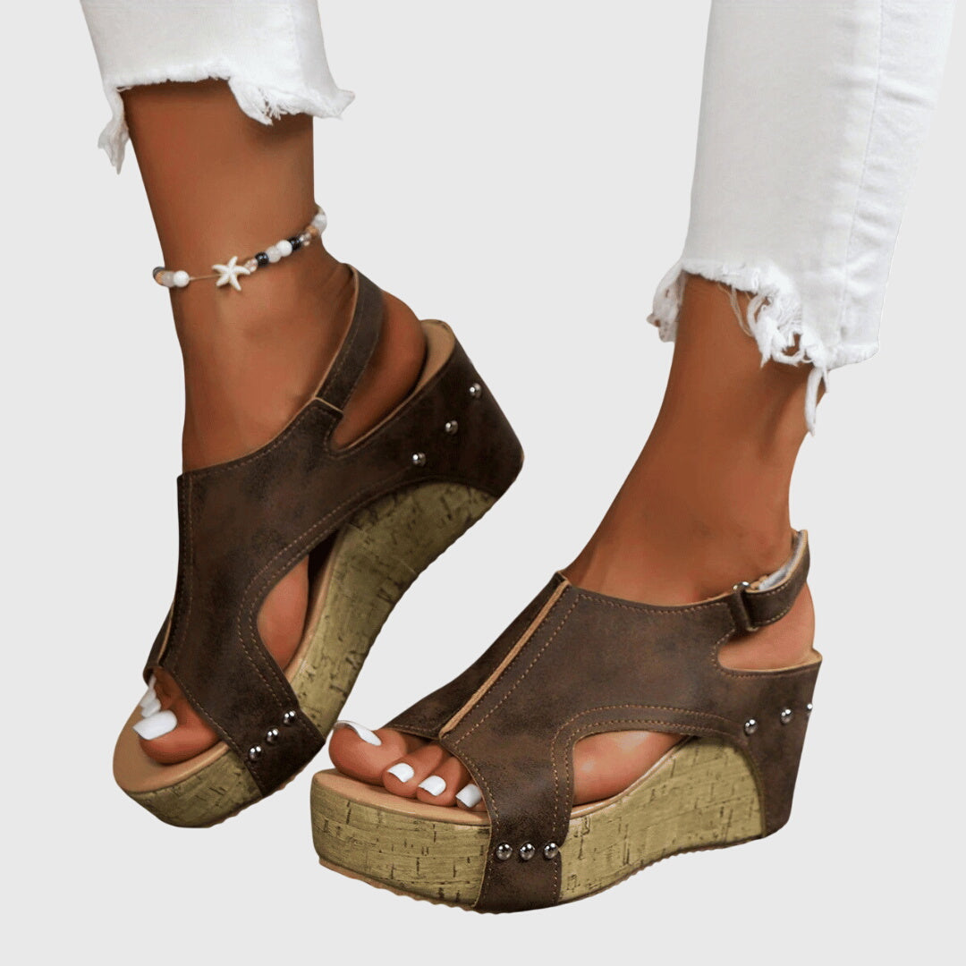 A woman in studded wedge sandals with an open front at a summer event.