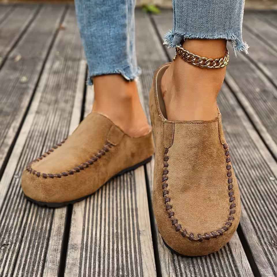 A pair of minimal slip-on loafers in warm brown with a soft footbed and open back