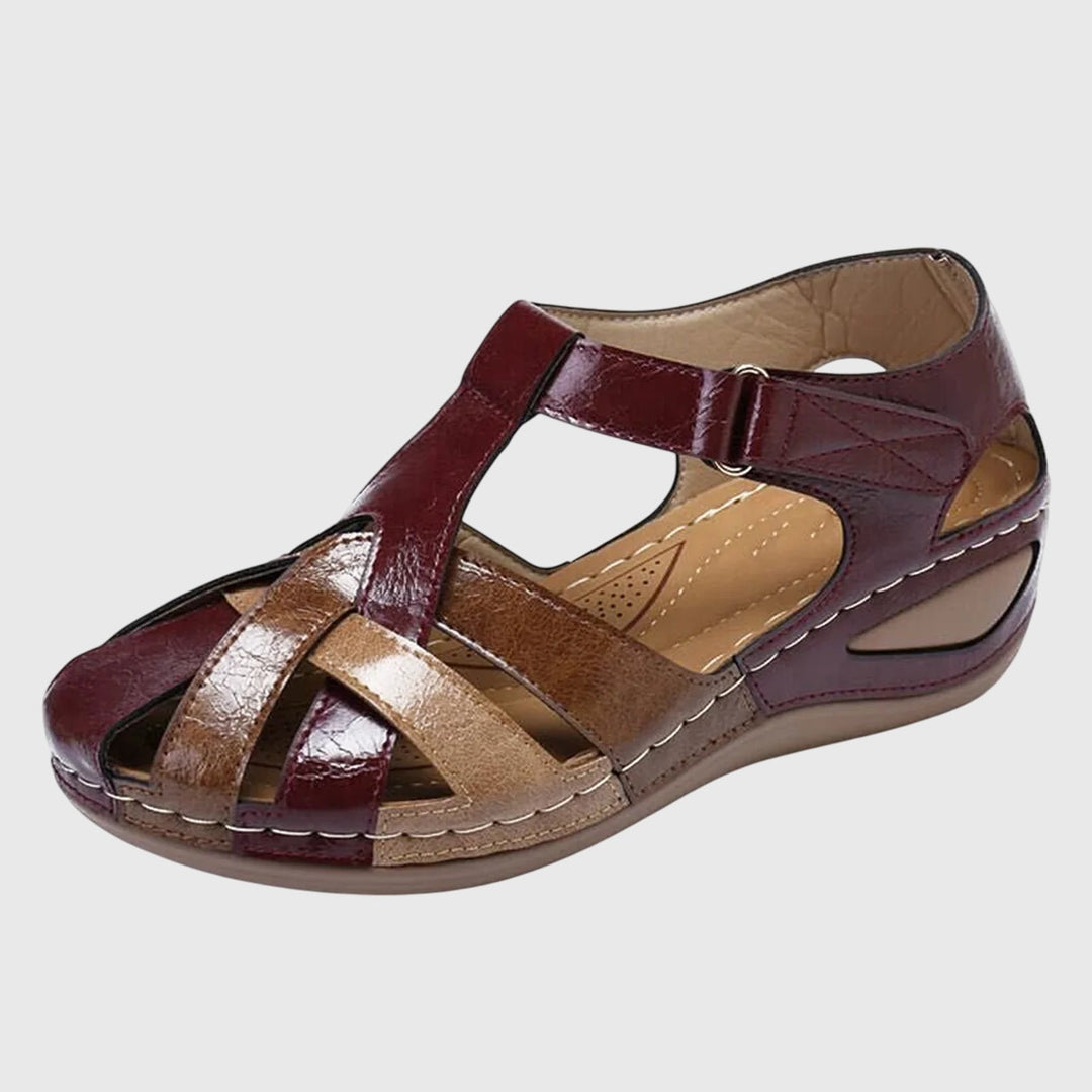 A woman in burgundy comfort sandals walking with ease on a sunny day, feet relaxed and supported.