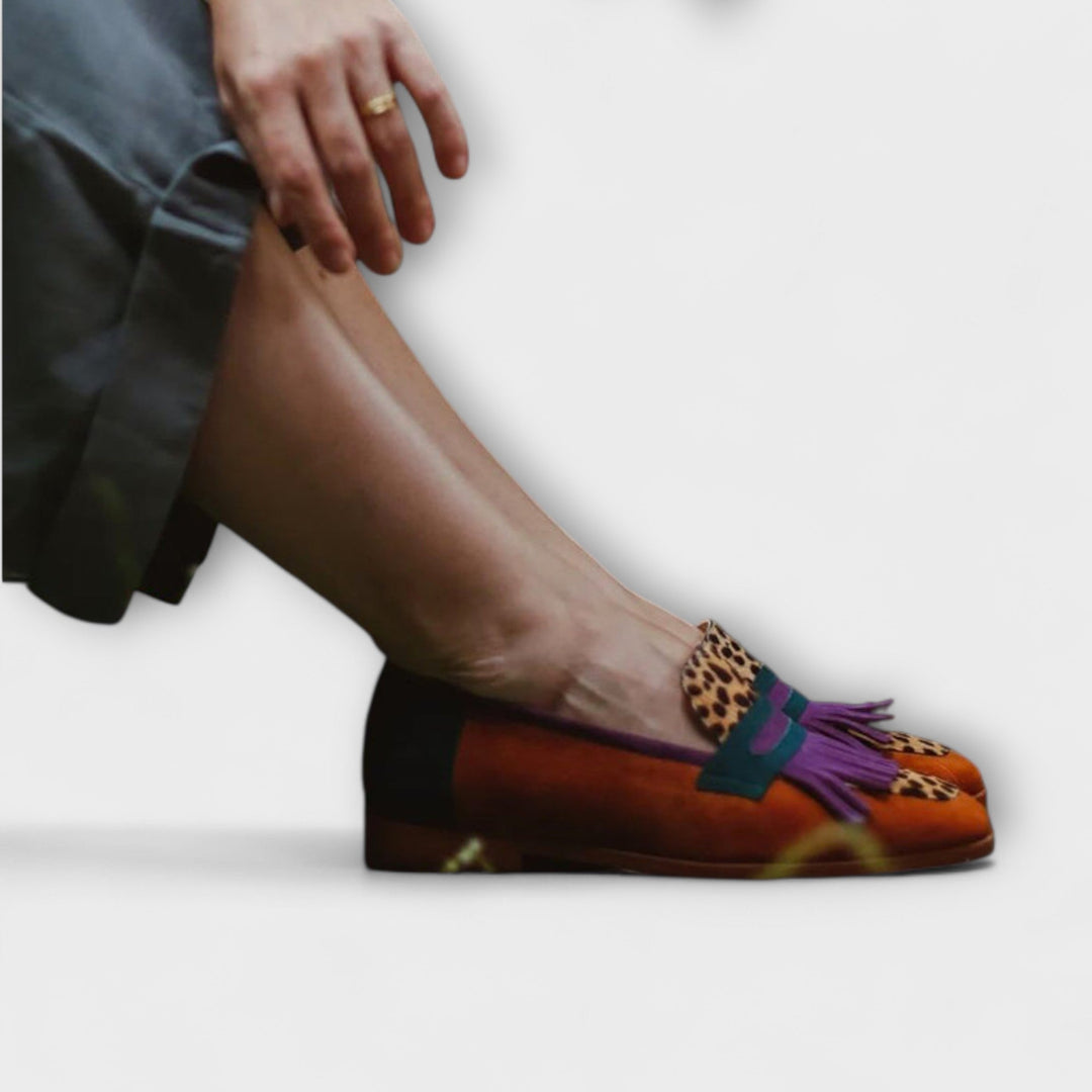 A woman wearing warm brown leopard-print loafers with autumn trousers, looking elegant and at ease.
