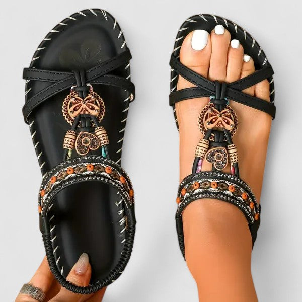 A woman walking comfortably outdoors in cushioned wide-fit orthopaedic sandals with a beaded T-strap and stretch slingback.