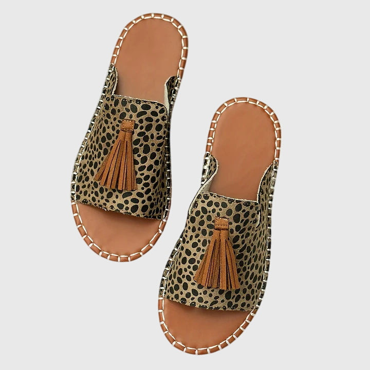A woman wearing colourful patterned boho slides with tassel details on a holiday day out.