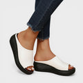 Open wedge mule sandals in white and brown with wide straps and a balanced wedge sole