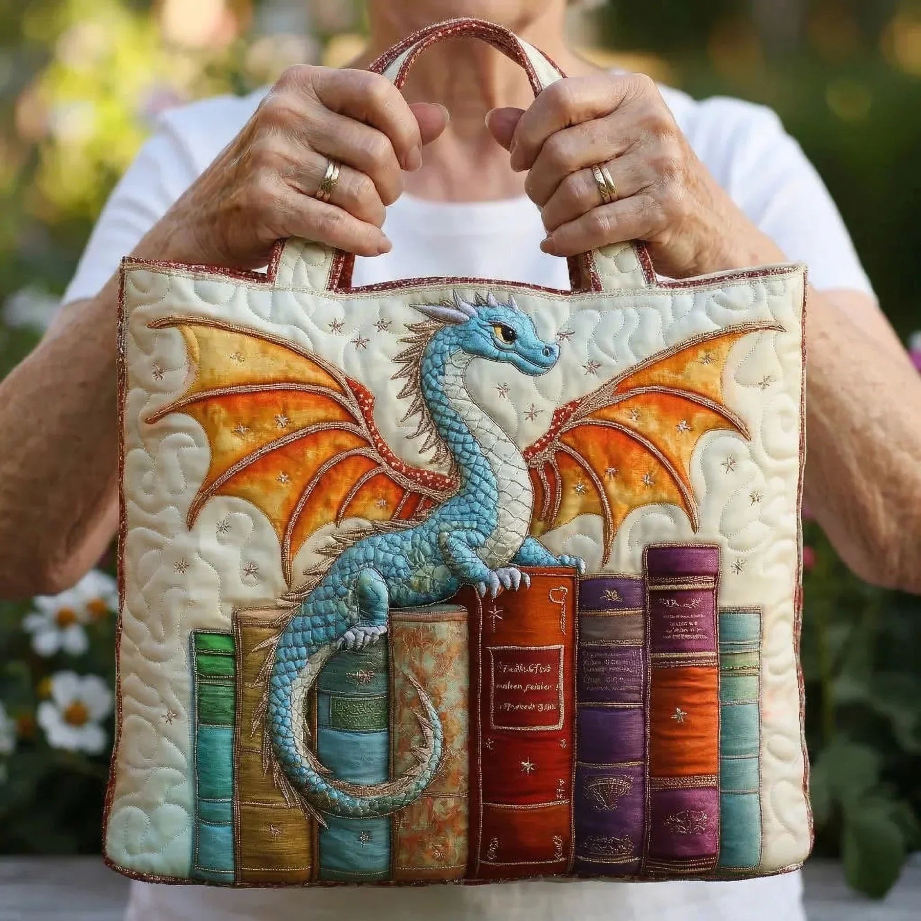 Quilted tote bag with an emerald green dragon coiled around a stack of books on a padded structured body