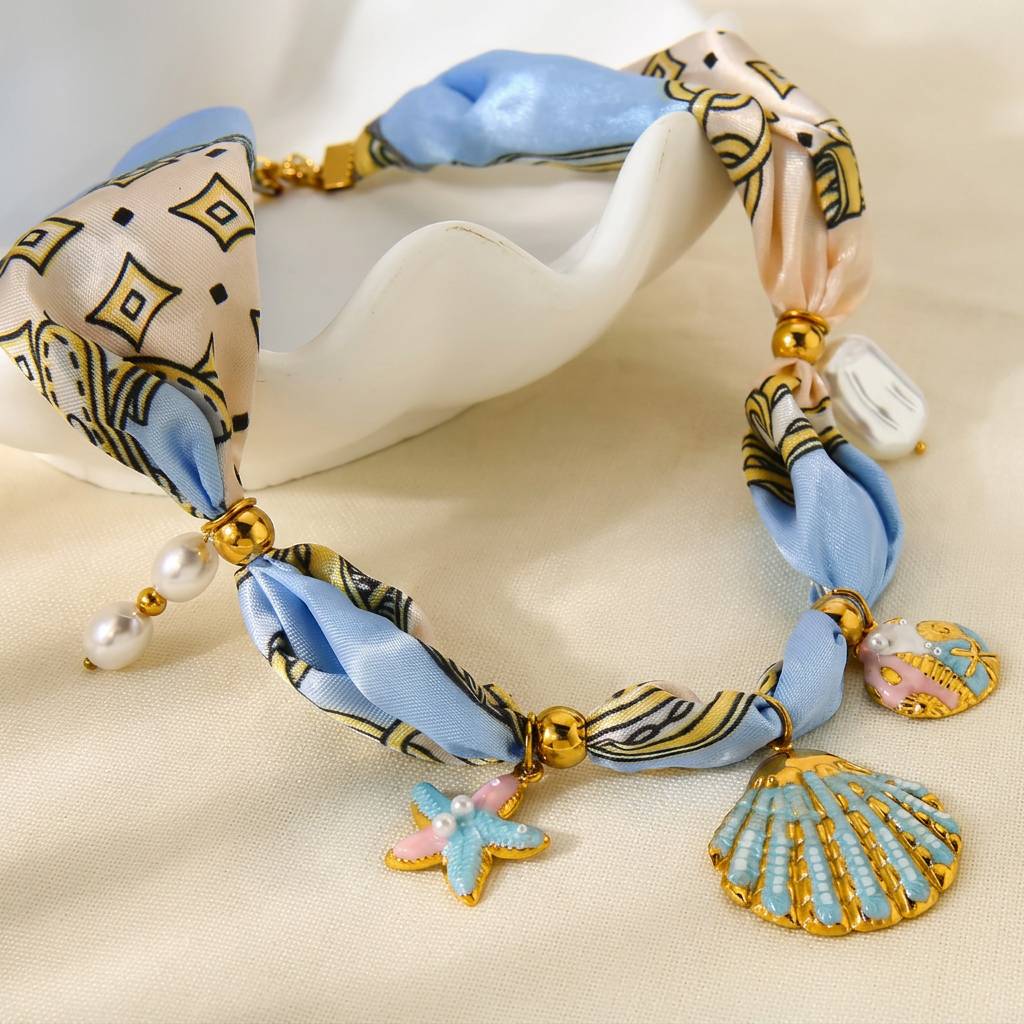 Delicate coastal necklace with shell charms, starfish and golden details on a soft ribbon
