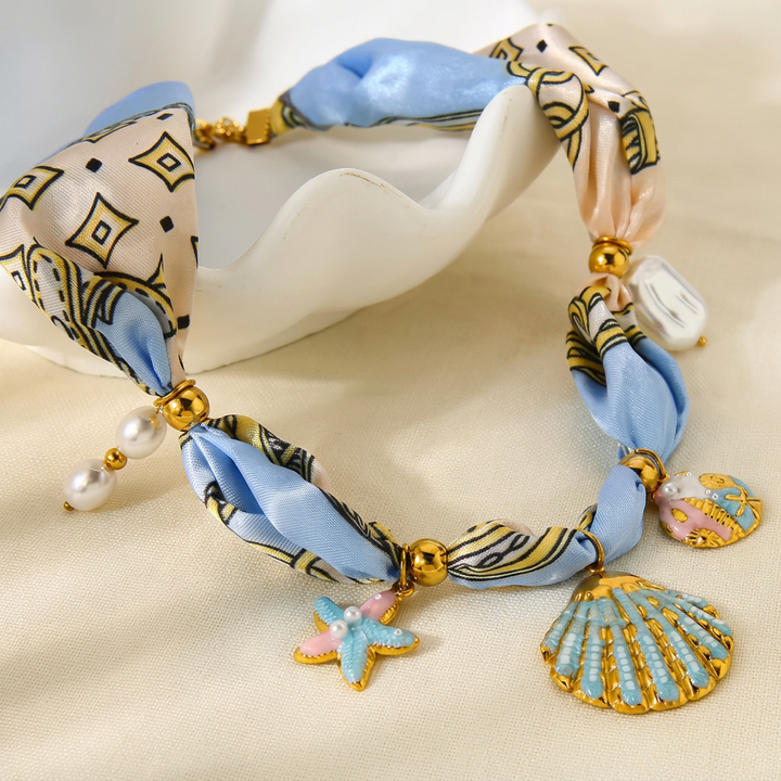 Delicate coastal necklace with shell charms, starfish and golden details on a soft ribbon