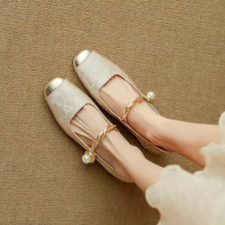 A woman wearing low-heel Mary Janes with a pearl-accented strap and a soft dress