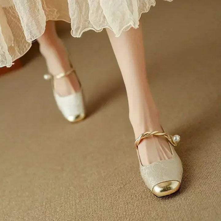 A woman wearing low-heel Mary Janes with a pearl-accented strap and a soft dress