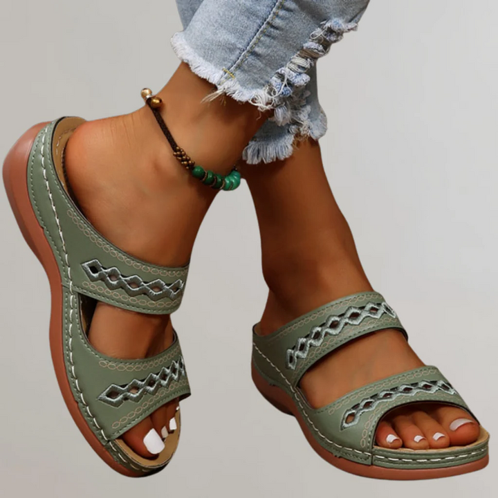 A woman walking comfortably in refined orthopaedic sandals with an adjustable strap.