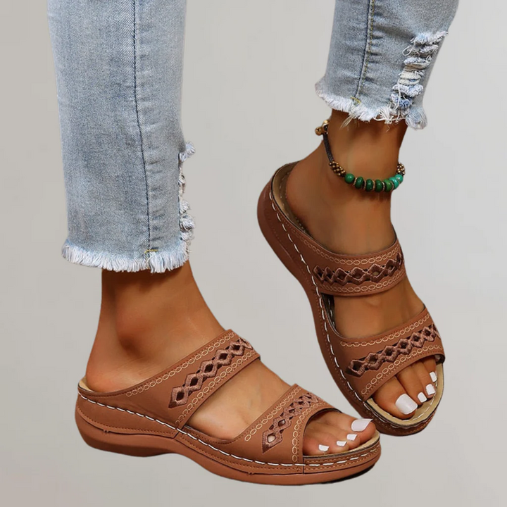 A woman walking comfortably in refined orthopaedic sandals with an adjustable strap.