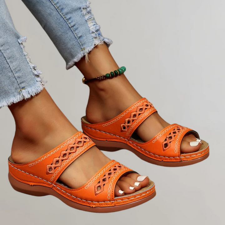 A woman walking comfortably in refined orthopaedic sandals with an adjustable strap.