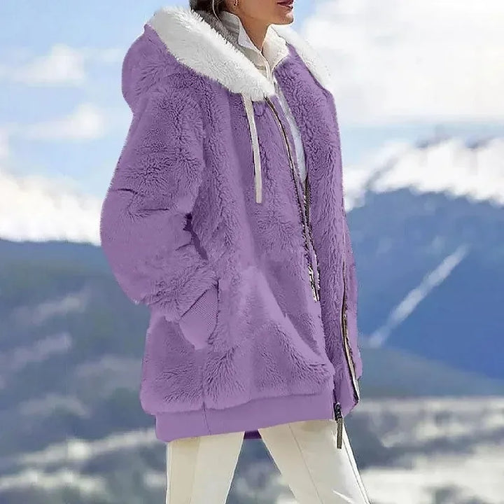 A woman wearing a hooded jacket with side pockets on a cold, rainy day out.