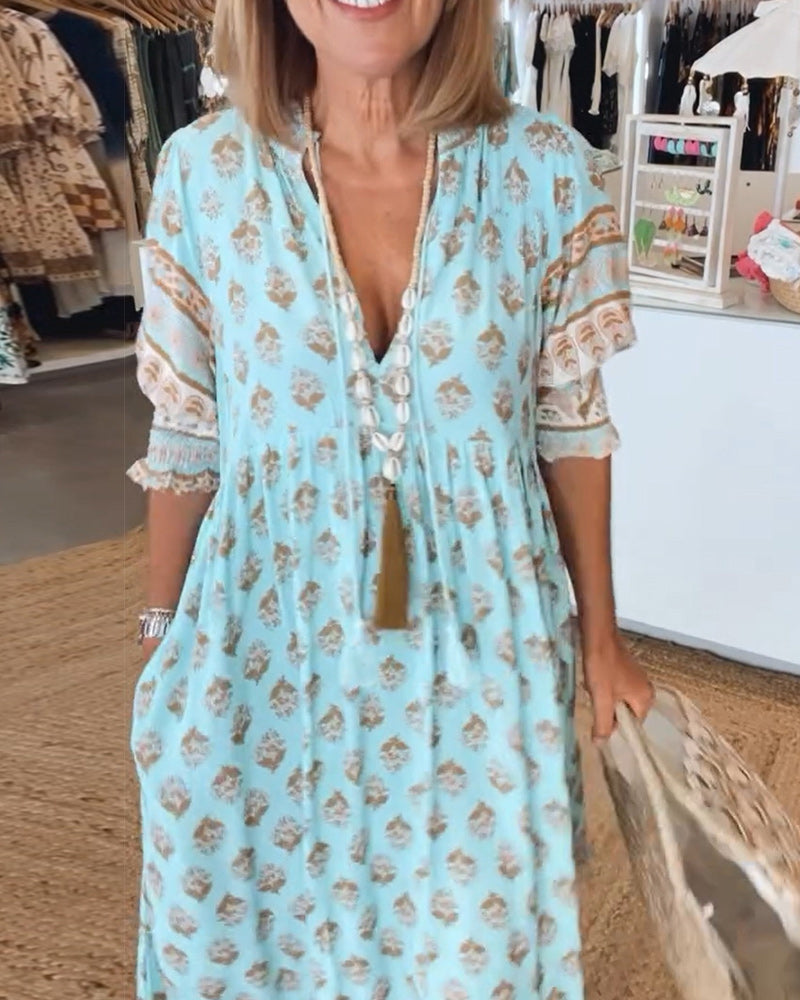 A woman wearing the Rosaleen boho beach dress with a flowing skirt, walking along the seaside.