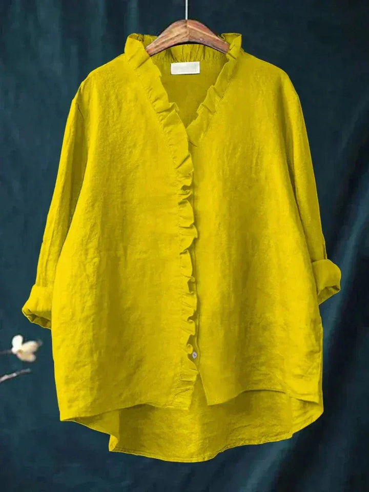 Woman wearing a plain ruffle-front summer blouse with a soft, flowing silhouette.