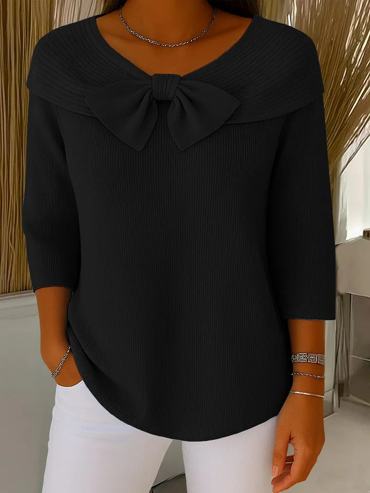 A woman wearing a shaped jumper with a soft bow detail, styled for a coffee date.