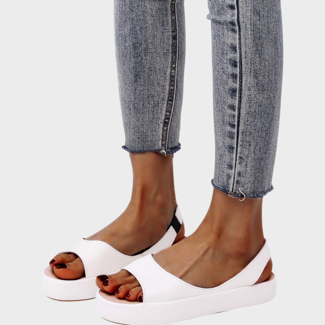 A woman walking gracefully in lightweight orthopaedic sandals with an adjustable strap on a sunny day.