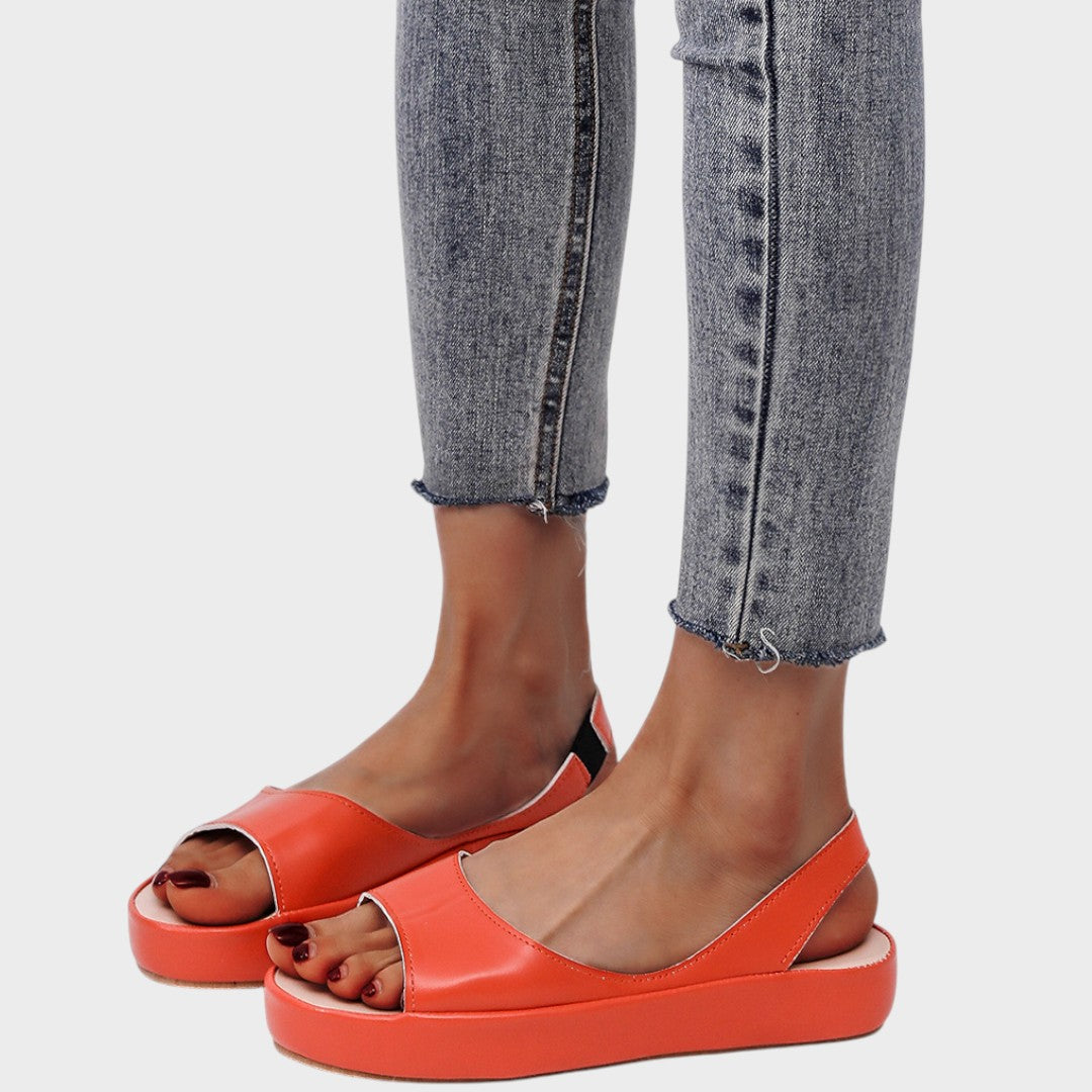 A woman walking gracefully in lightweight orthopaedic sandals with an adjustable strap on a sunny day.