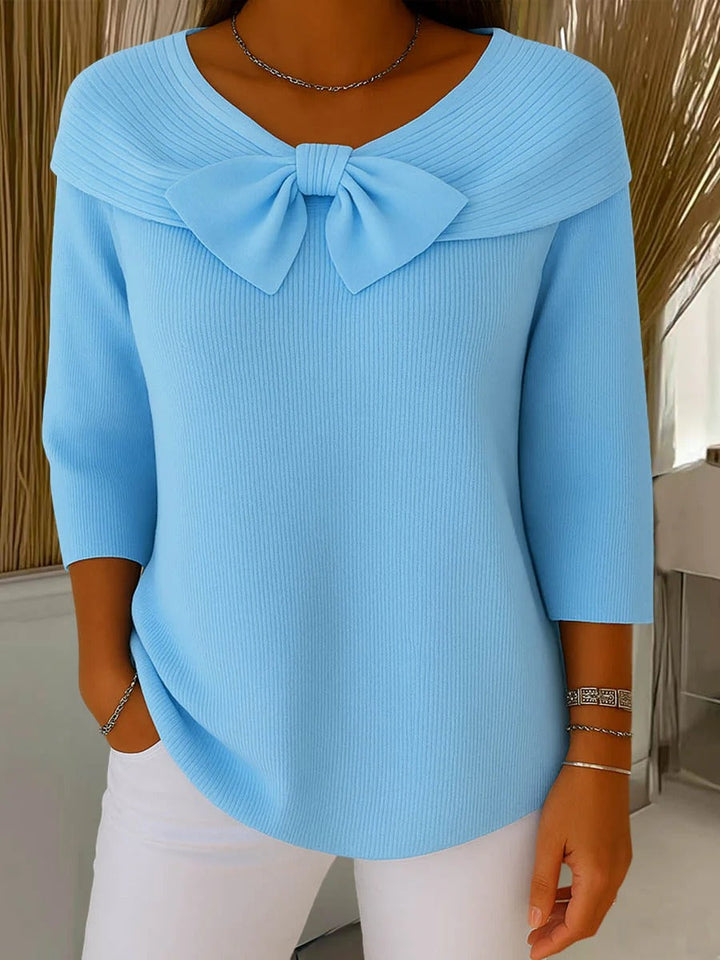 A woman wearing a shaped jumper with a soft bow detail, styled for a coffee date.