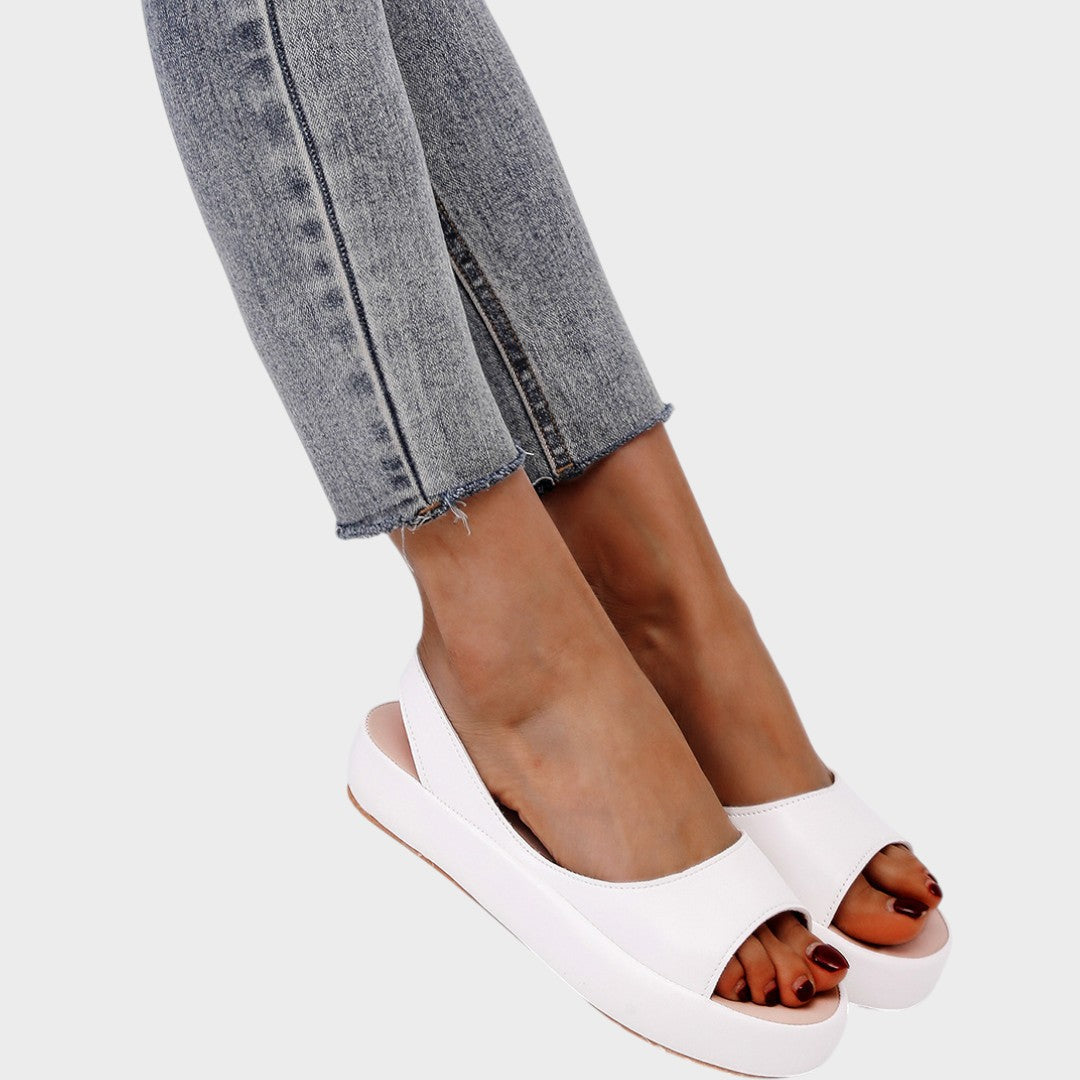 A woman walking gracefully in lightweight orthopaedic sandals with an adjustable strap on a sunny day.