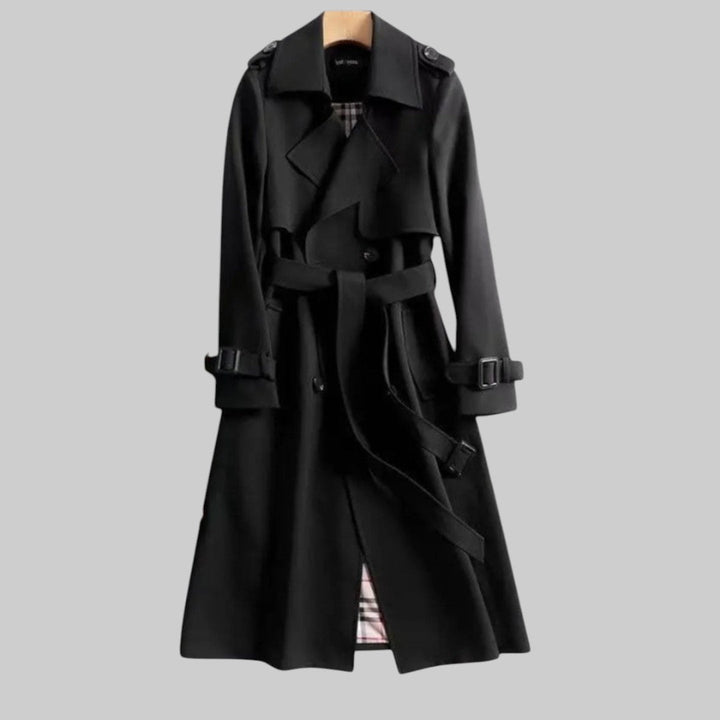 A woman wearing a belted classic trench coat with a defined waist, walking through the city.
