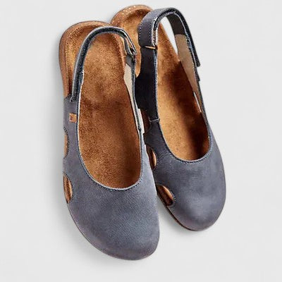 A woman wearing soft grey cut-out comfort sandals with an adjustable back strap on a relaxed weekend.
